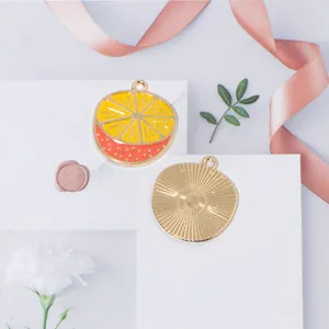 Macro view of round lemon and orange enamel fruit charms with golden textured back
