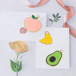 Detailed view of enamel fruit charms including peach, banana, and avocado for DIY jewelry