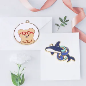 Détail de breloques en émail ours et baleine pour bijoux DIY sur un fond en tissu doux