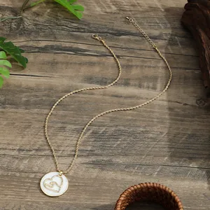 Golden heart and shell round necklace on dark wood background with natural lighting