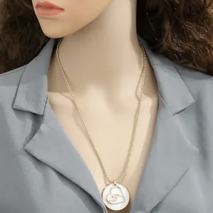 Close-up of golden heart pendant with white shell inlay worn by model on a rope chain