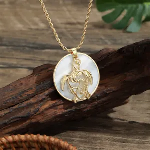 Golden rope chain necklace with a natural white shell turtle pendant on dark wood
