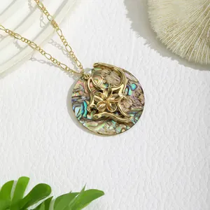 Macro view of golden pendant necklace with iridescent shell and intricate floral metalwork