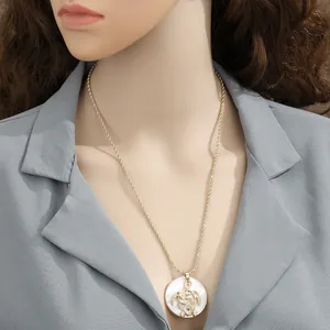 Close-up of golden sea turtle necklace with white mother-of-pearl pendant on model