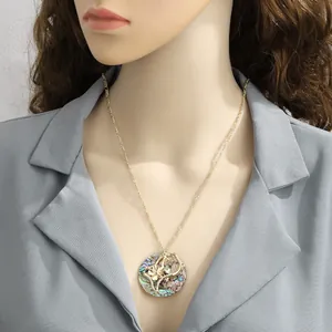 Detail of a round gold shell pendant necklace with intricate floral cutout on a model
