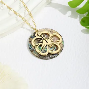Macro view of gold hibiscus flower overlay on iridescent shell pendant necklace