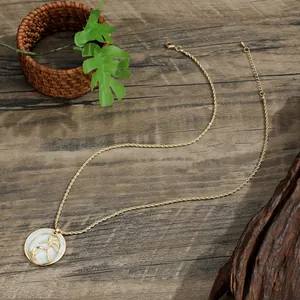 Detail of gold tropical coconut tree pendant with white shell inlay on a twisted chain