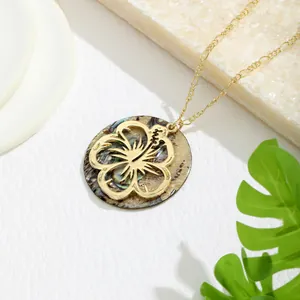 Detail of tropical hibiscus pendant with natural shell inlay on gold Figaro chain
