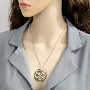 Close-up of gold shell pendant necklace with floral patterns worn by a model
