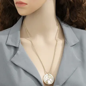 Detail of a gold rope chain necklace featuring a tropical palm tree shell pendant