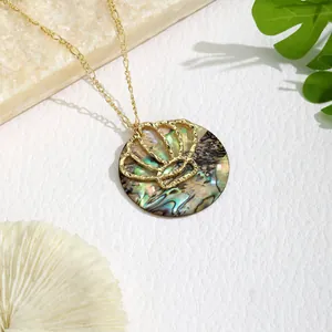 Detailed close-up of golden Figaro chain with shell inlay pendant on stone texture