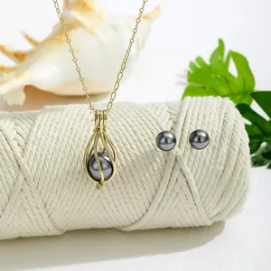 Detailansicht des grauen Perlen-Schmucksets mit goldenem Hohl-Anhänger auf Baumwollseil