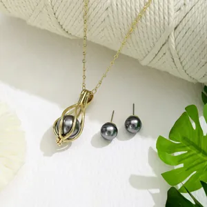 Detailaufnahme von hohlkäfig goldkette und dunkelgrauen perlenohrringen set