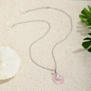 Collana marina argentata con vetro marino rosa, perla e delfino su fondo sabbia