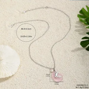 Collana con ciondolo delfino rosa con vetro marino e perla su sfondo a tema spiaggia