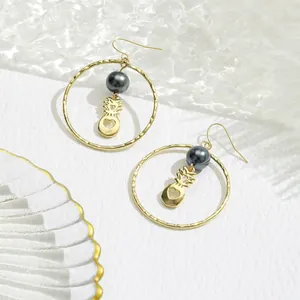 Détail de boucles d'oreilles créoles martelées avec perle grise et pendentif ananas chic