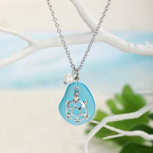 Dettaglio del ciondolo tartaruga in vetro marino con perla su decoro corallo