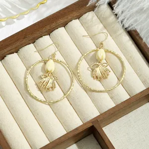 Créoles dorées avec boutons de fleurs blanches et nœuds sur un plateau à bijoux en bois