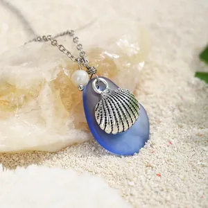 Dettaglio del ciondolo in vetro marino blu con rilievo di conchiglia argento e perla bianca