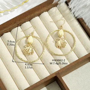 Détail de boucles d'oreilles créoles dorées avec perles tulipes et pendentifs en métal