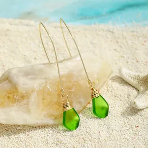 Handgefertigte grüne Meerglas-Ohrringe mit Golddrahtwicklung auf feinem Sand