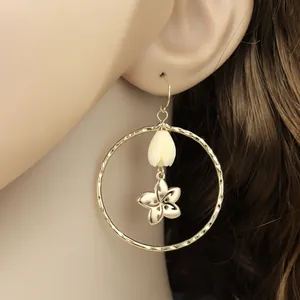 Gros plan de boucles d'oreilles créoles dorées avec perle tulipe et pendentifs fleurs