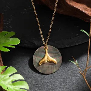 Vue détaillée du collier queue de baleine dorée avec un pendentif en nacre sombre