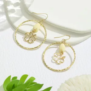 Détails des boucles d'oreilles créoles dorées avec pétales blancs et perles