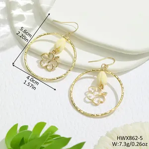Détail de boucles d'oreilles fleur évidée dorées avec perles et dimensions en pouces
