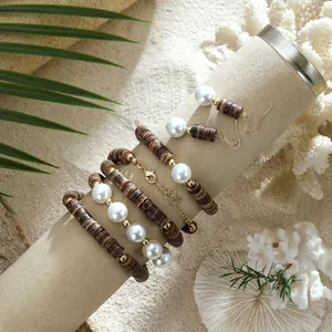 Detail eines Boho-Schmucksets mit dunklen Holzscheiben und weißen Perlen auf Sand