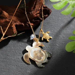 Hawaiian turtle pendant necklace with natural shell inlay and gold chain on stone