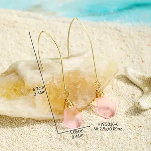 Makro-Detail von handgefertigten rosa Seeglas-Ohrringen mit Drahtwicklung auf Sand