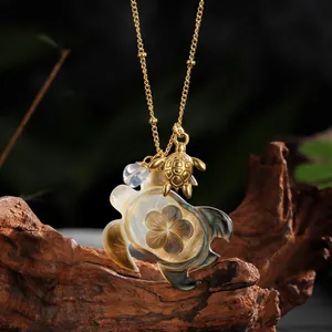 Detail of Hawaiian ocean necklace with carved shell sea turtle pendant and golden charms