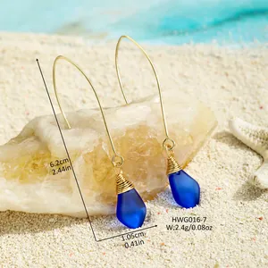 Handgefertigte blaue Meeresglas-Ohrringe mit Golddrahtwicklung auf Sand mit Seestern
