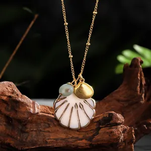 Detail of seashell pendant necklace with gold accents on a rustic wood background