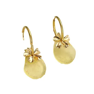 Minimalistische goldene Blumenohrringe mit gelben birnenförmigen Tropfenanhängern auf Weiß
