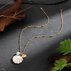Close-up of shell and starfish charms on a gold beaded chain with a natural stone backdrop