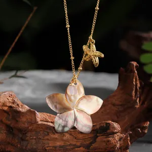 Macro detail of mother-of-pearl flower necklace with golden starfish charm