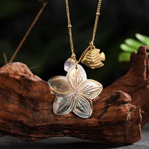 Detail of vintage necklace with iridescent shell flower, gold fish, and amethyst stone