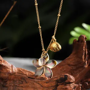 Detailed shot of golden necklace with iridescent shell flower and sea shell pendant