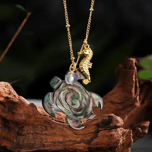 Macro shot of gold necklace featuring rose-carved shell turtle and seahorse charms