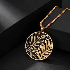 Detalle del collar dorado con diseño de hoja de palma calada y esmalte negro lujo