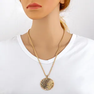 Elegante collar con colgante circular de hoja de palmera hueca dorada en un maniquí