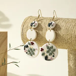 Handmade clay floral dangle earrings with colorful botanical patterns and gold hooks
