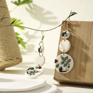 Detail of floral drop earrings with white clay discs and handcrafted leaf relief