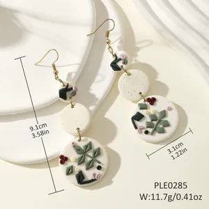 Macro detail of long floral drop earrings featuring white clay petals and red flower relief
