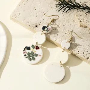 Minimalist handmade polymer clay earrings with floral relief on stone base and foliage