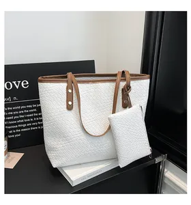 Detail van witte geweven shopper set met bruine lederen handvaten en bijpassend tasje