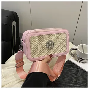 Detail of crossbody bag featuring pink faux leather, woven panel, and silver M logo