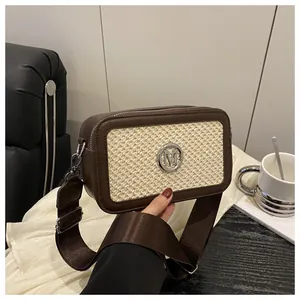 Detail of vintage box bag with silver M logo and wide brown shoulder strap on a sofa